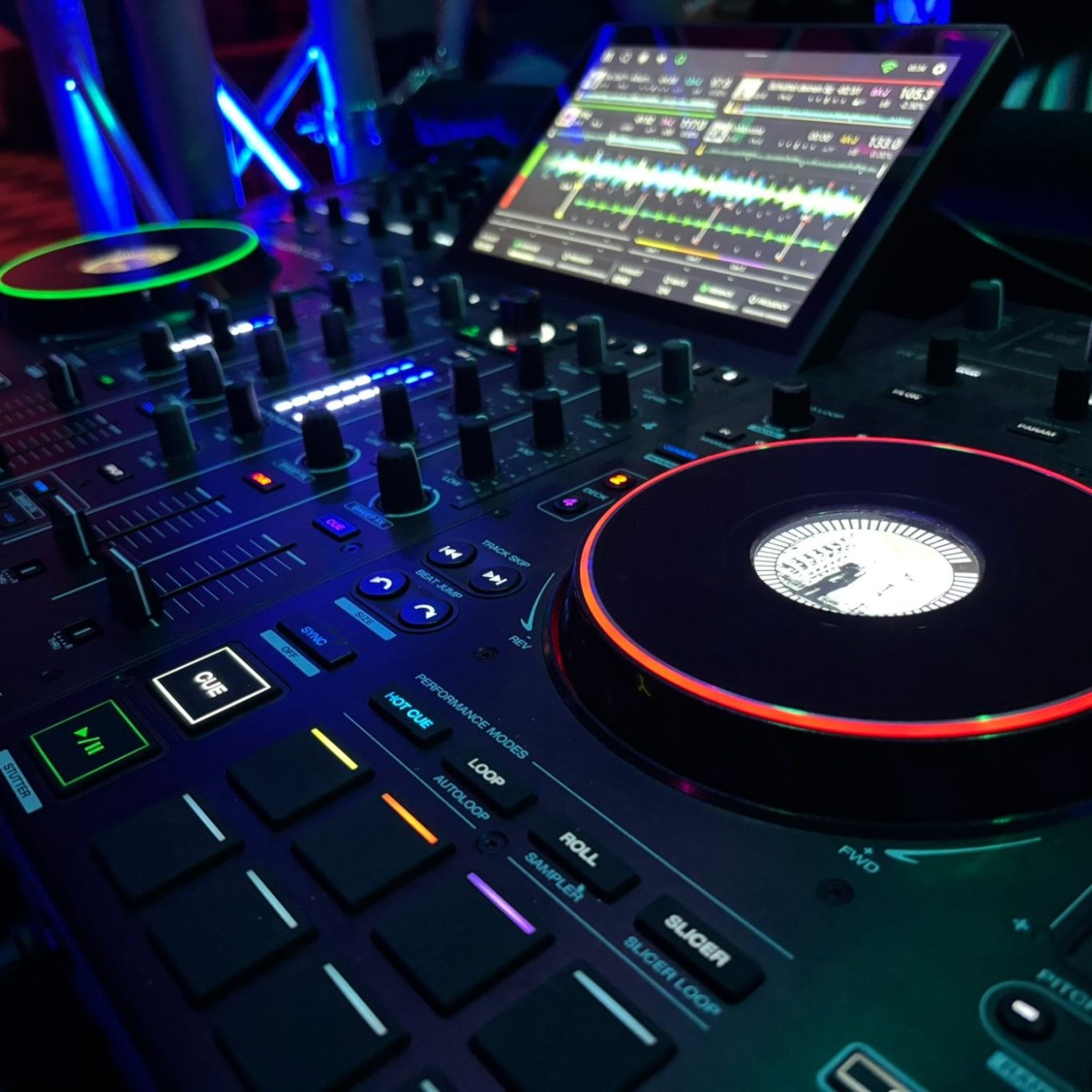 DJ-Service für Events jeder Art DJ-Controller mit bunten Lichtringen und Touchscreen in einer Club-Umgebung.